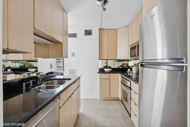 a kitchen with stainless steel appliances granite countertop a sink a stove and a refrigerator