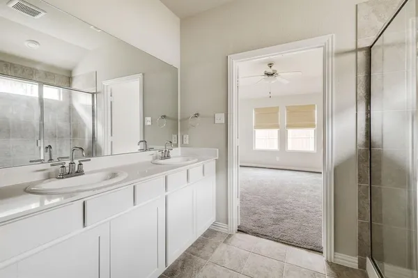 a bathroom with a double vanity sink mirror and shower