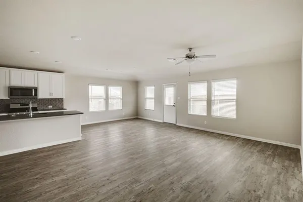 a view of an empty room with window and wooden floor