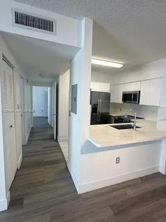 a large white kitchen with wooden floor and a sink