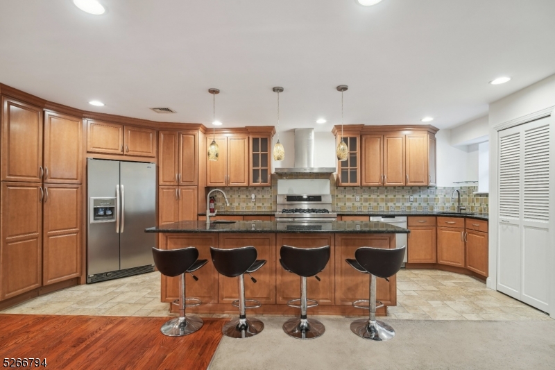 a kitchen with stainless steel appliances granite countertop a table chairs sink refrigerator and microwave