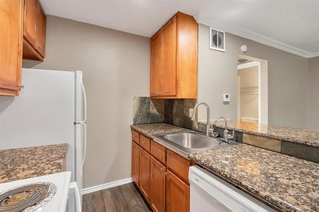 a kitchen with granite countertop a sink and a refrigerator