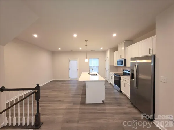 a kitchen with stainless steel appliances a refrigerator a sink a stove a microwave a center island and wooden floor