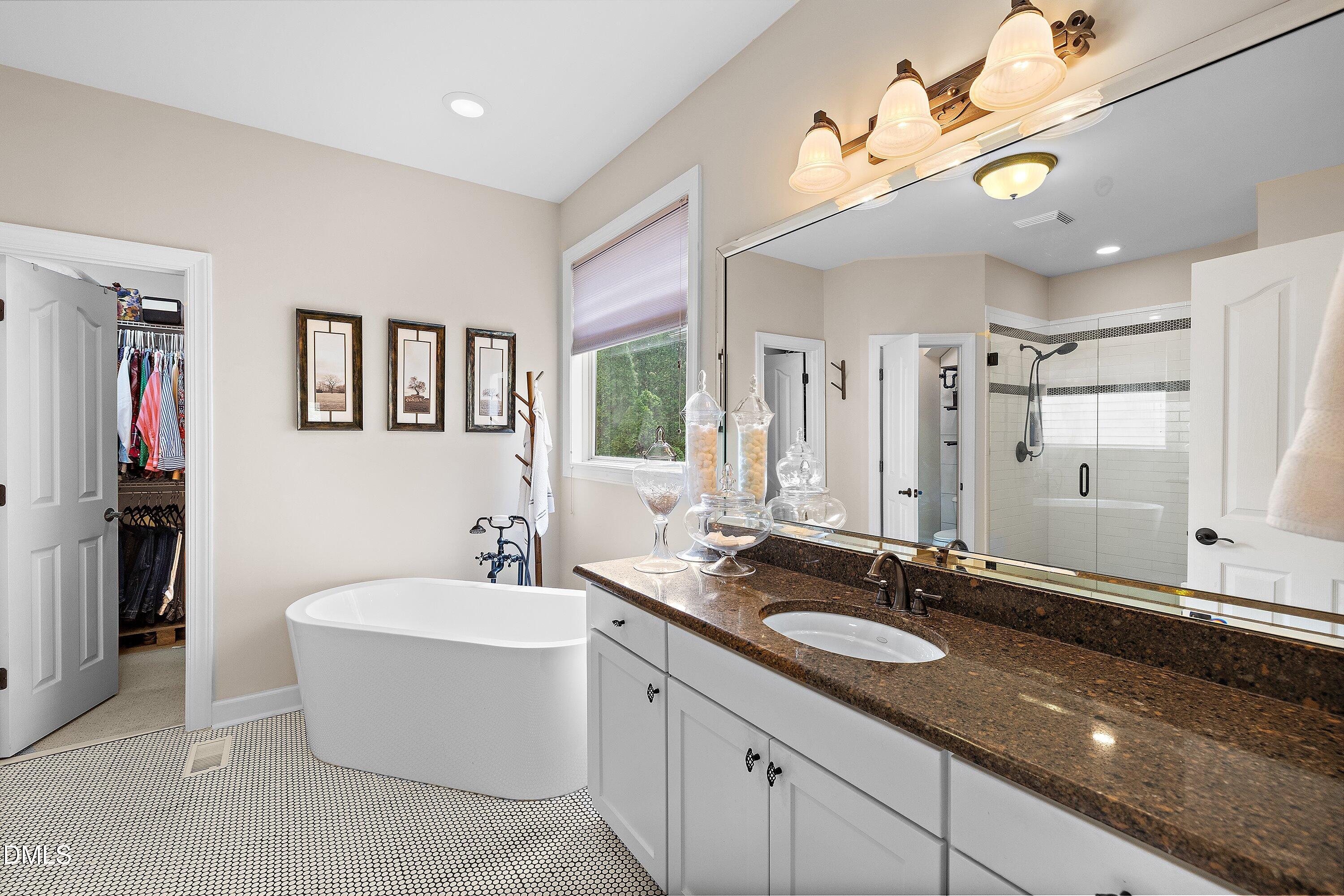 701 Royal Tower Way Cary, NC 27513 - Photo 37 of 82 a bathroom with a granite countertop sink a large mirror and a bathtub