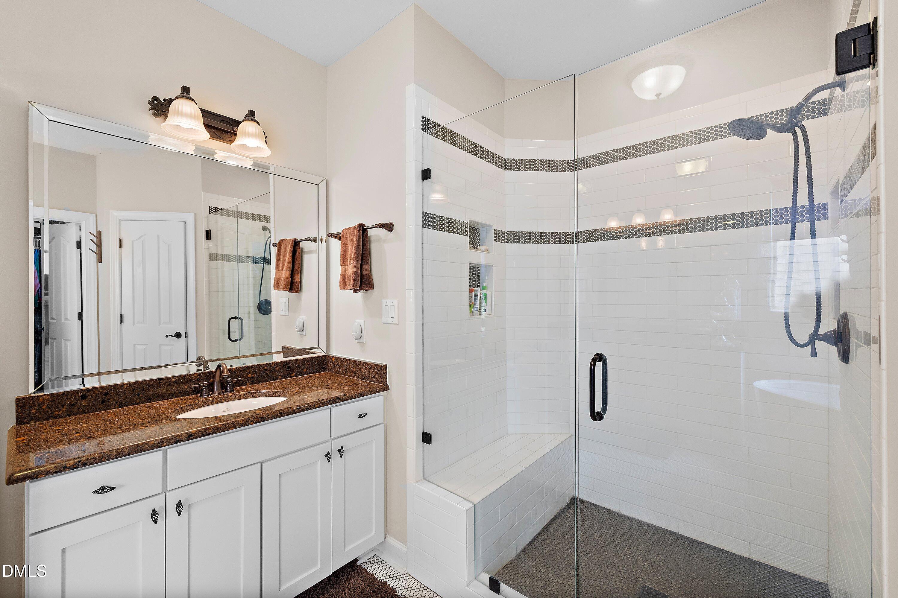 701 Royal Tower Way Cary, NC 27513 - Photo 40 of 82 a bathroom with a granite countertop sink a mirror a shower and a bathtub