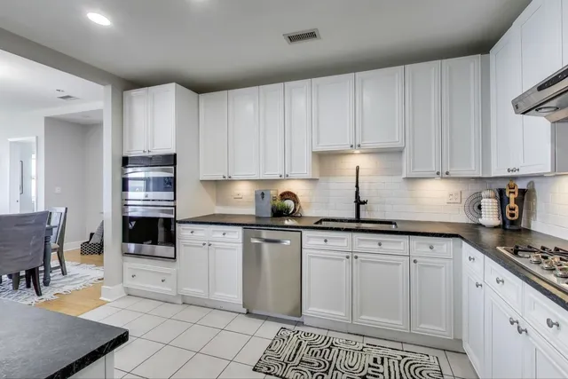 a kitchen with a sink dishwasher a stove a microwave oven and white cabinets