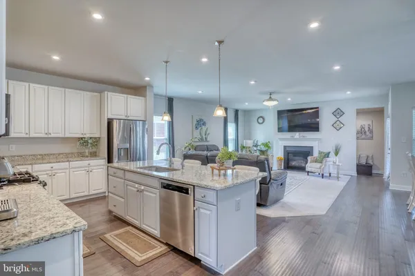 a kitchen with stainless steel appliances kitchen island granite countertop a stove top oven a sink a dining table and chairs