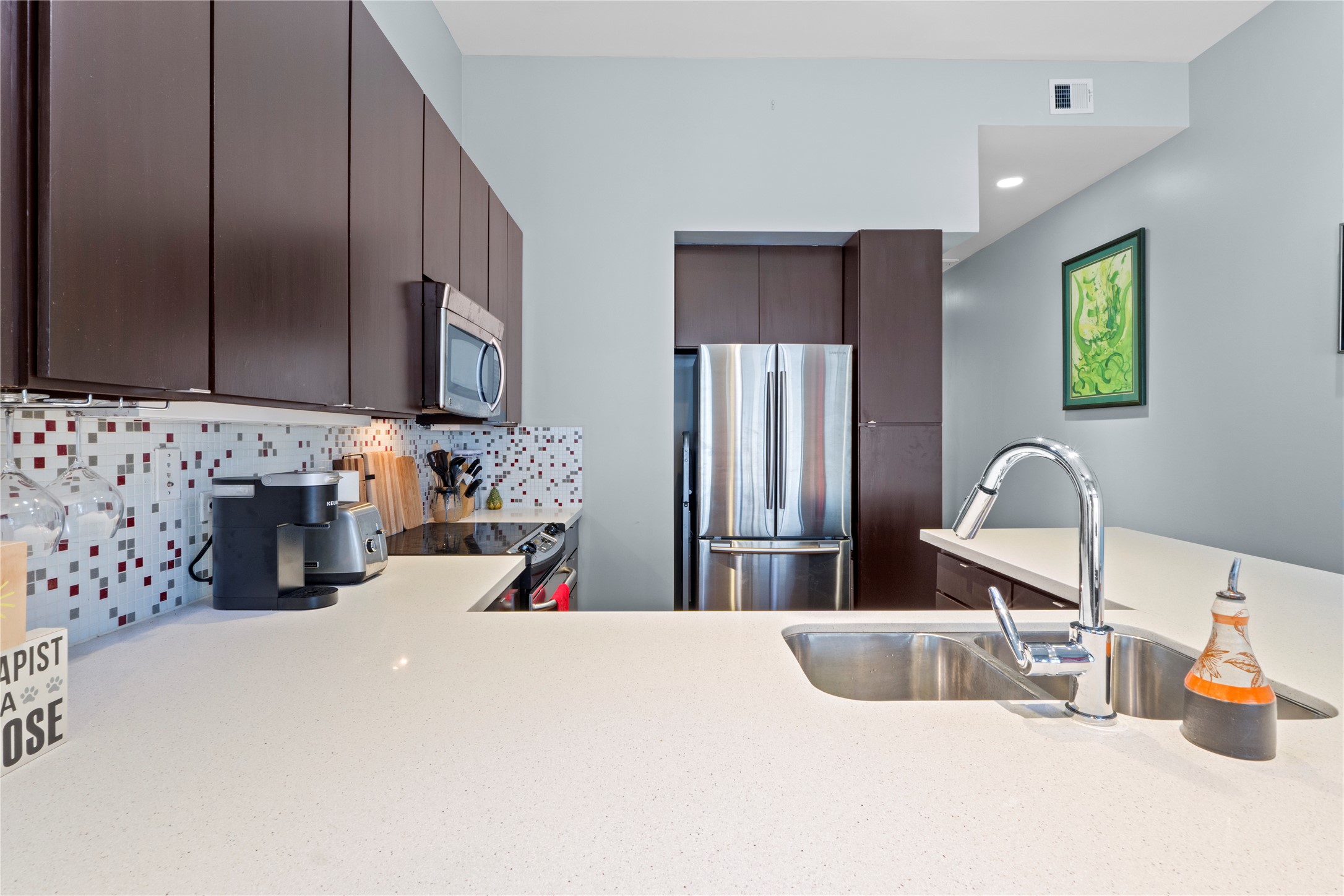 507 Sabine Street, Unit 509 Austin, TX 78701 - Photo 5 of 23 Kitchen with dark brown cabinetry, stainless steel appliances, light countertops, tasteful backsplash, and recessed lighting