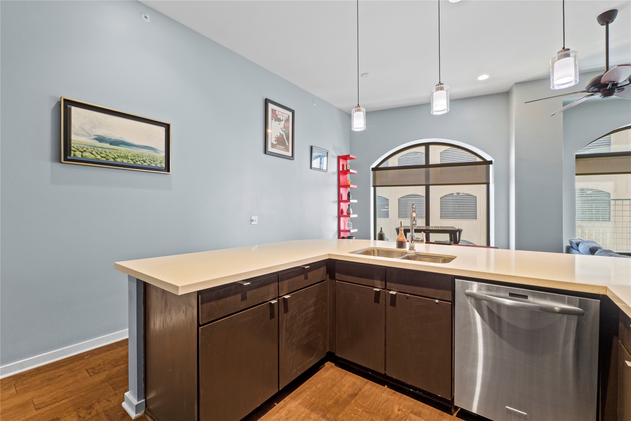 507 Sabine Street, Unit 509 Austin, TX 78701 - Photo 6 of 23 Kitchen with dark brown cabinetry, dishwasher, light wood-style floors, and decorative light fixtures