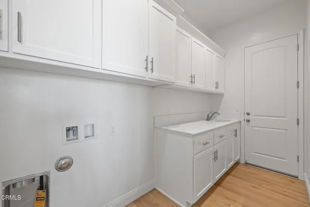 a large white kitchen with cabinets wooden floor and a sink