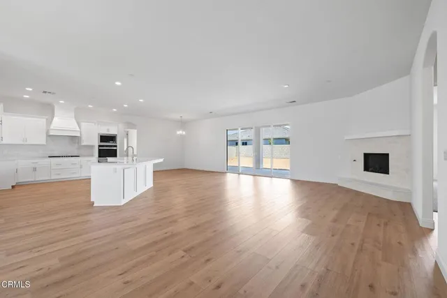 a view of an empty room with wooden floor and a fireplace