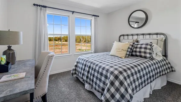a bedroom with a bed and a lamp on desk