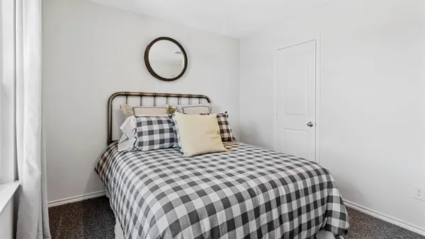 a bedroom with a bed a dresser and windows