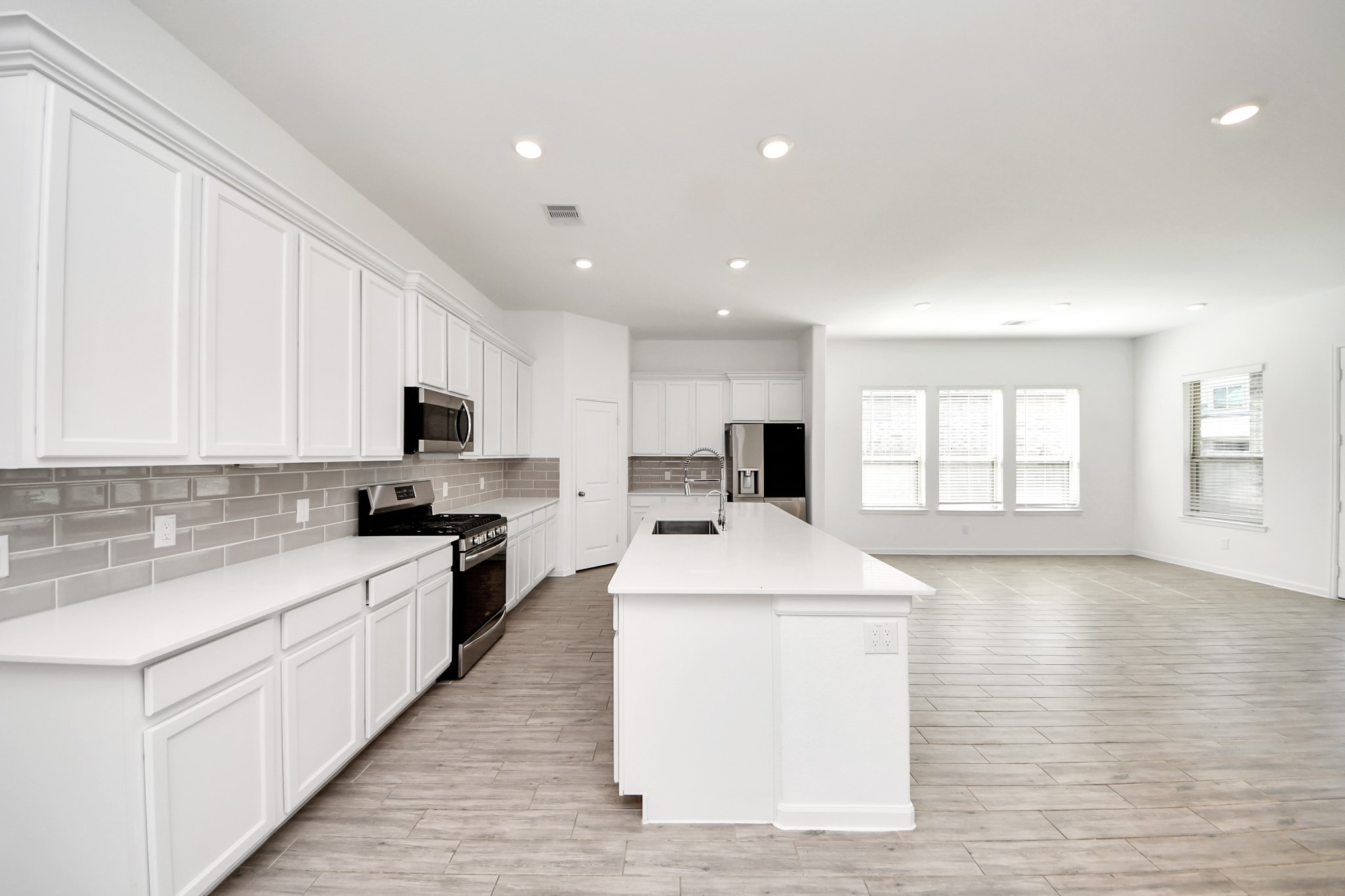 17770 Misty Brook Lane Conroe, TX 77302 - Photo 11 of 50 a large white kitchen with kitchen island a stove a sink a refrigerator and cabinets