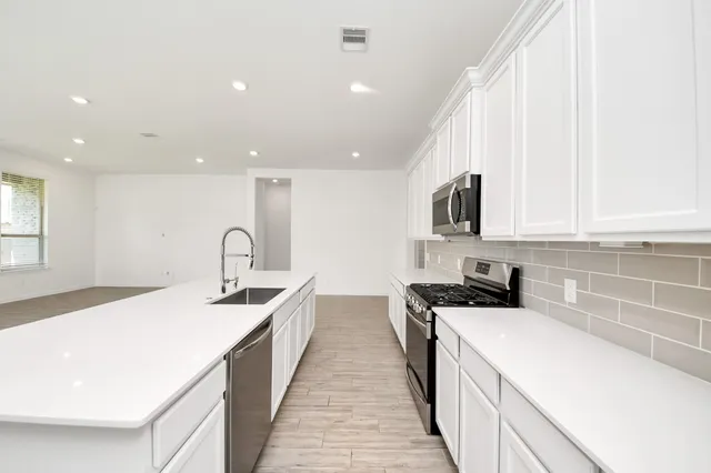 a large white kitchen with kitchen island a stove a sink a refrigerator and cabinets