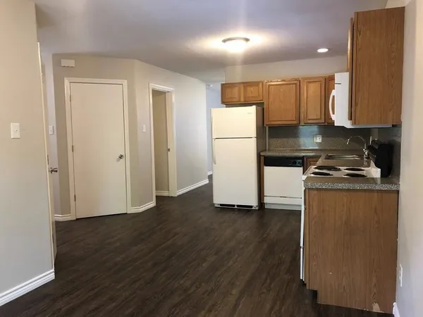 a kitchen with a refrigerator a stove and wooden floor