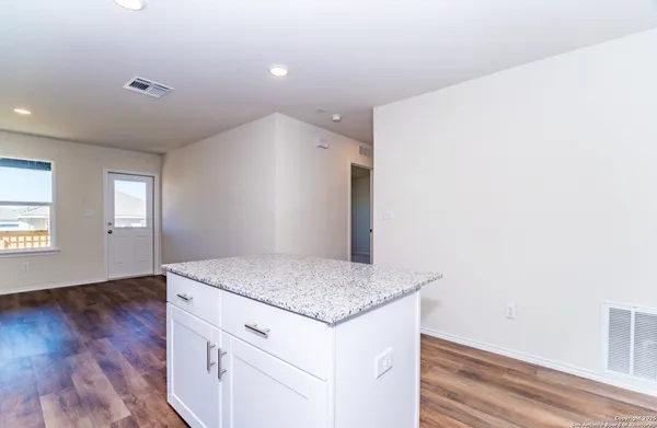 a kitchen with granite countertop white cabinets and wooden floor