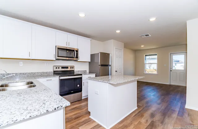 a large kitchen with stainless steel appliances granite countertop a stove a sink and a microwave