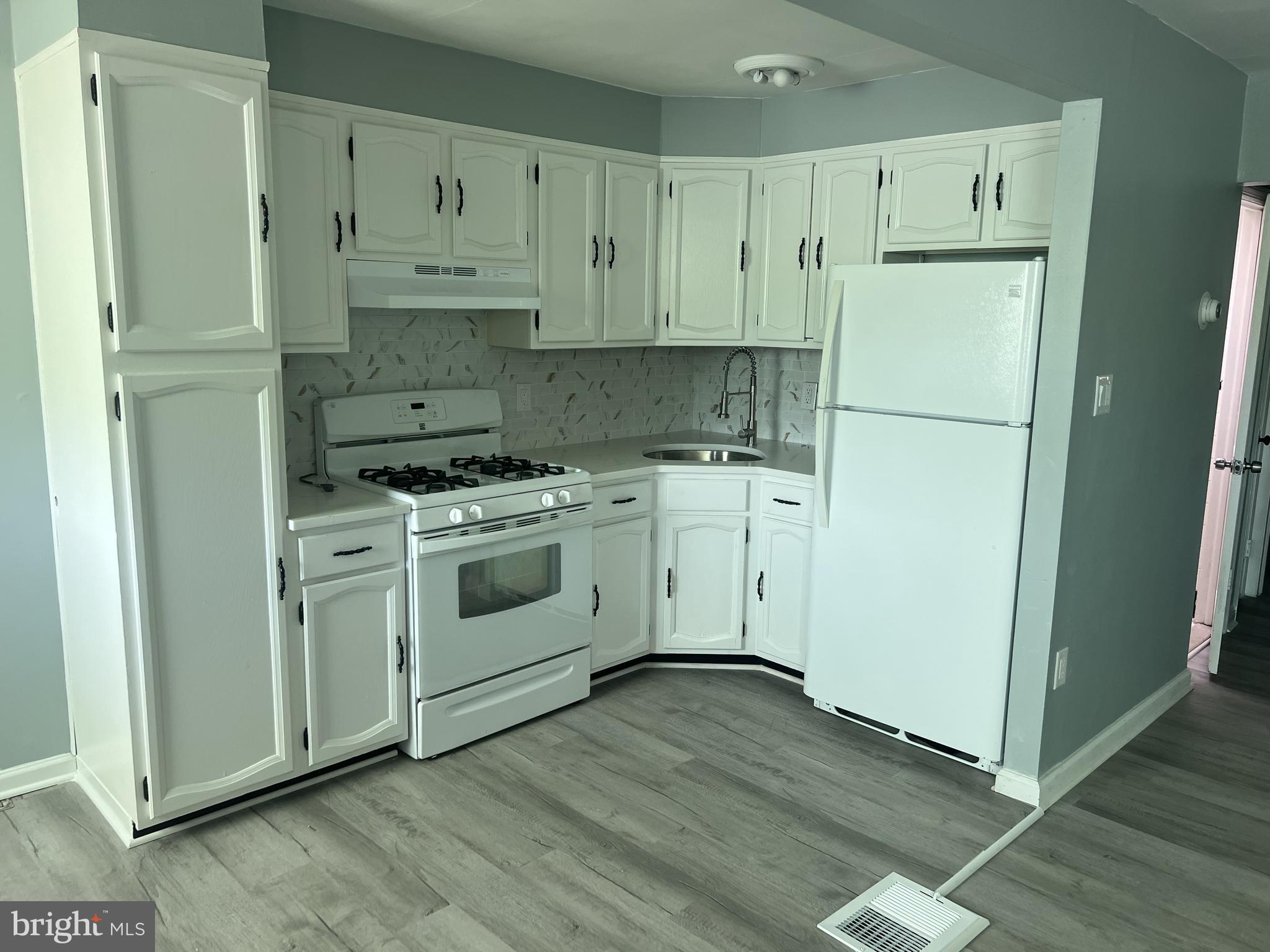 6526 Keystone Street Philadelphia, PA 19135 - Photo 2 of 7 a kitchen with white cabinets and white appliances