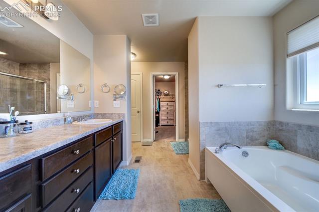 11353 Avena Road Peyton, CO 80831 - Photo 30 of 46 Bathroom with tile flooring, double vanity, and tub plus walk in shower