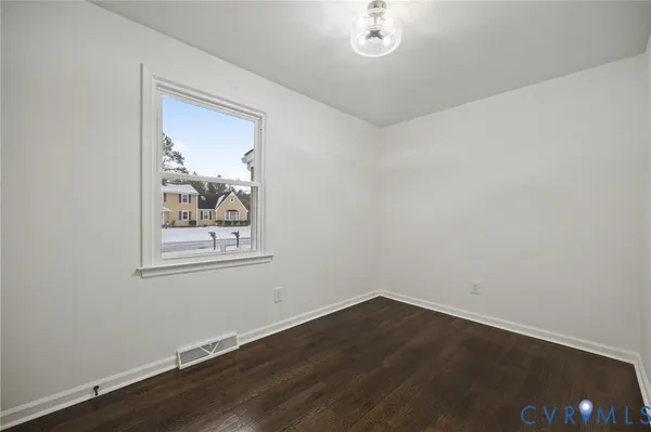 an empty room with wooden floor mirror and windows