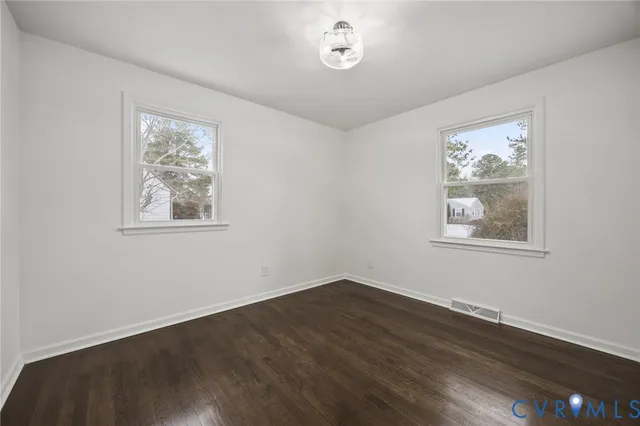 a view of a big room with wooden floor and windows