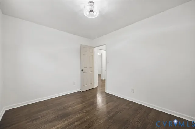 an empty room with wooden floor and ceiling fan