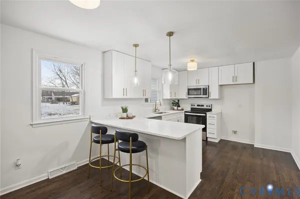 a kitchen with stainless steel appliances a white table chairs and a refrigerator