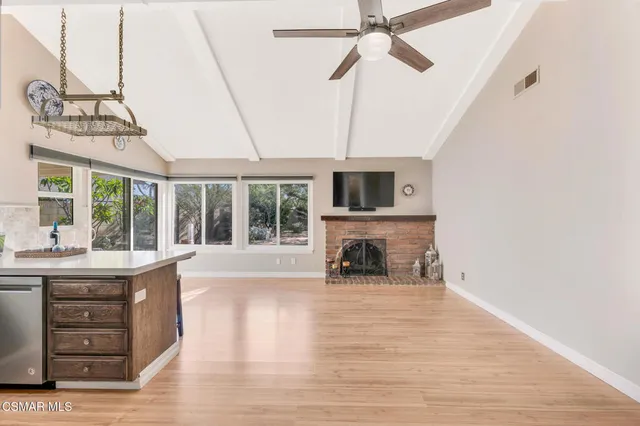 a view of a livingroom with a fireplace a ceiling fan and wooden floor