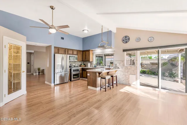 a view of a kitchen with dining area wooden floor and electric appliances