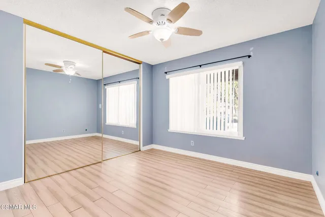 a view of an empty room with window and a chandelier fan