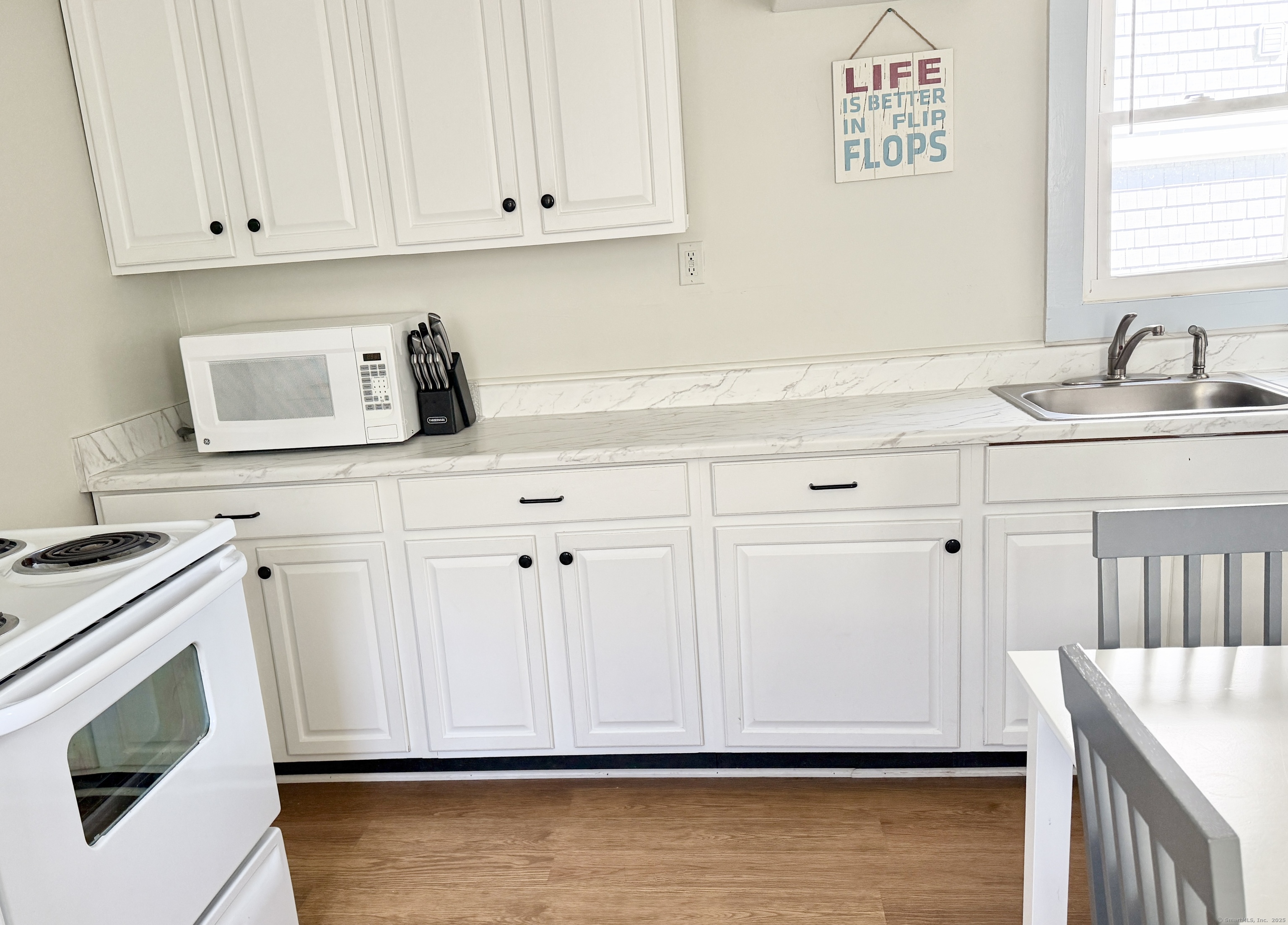 102 Chalker Beach Road Old Saybrook, CT 06475 - Photo 16 of 22 a kitchen with white cabinets and sink