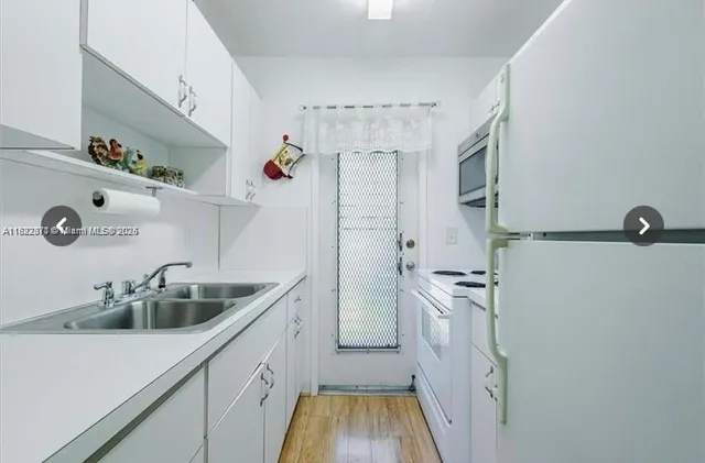 a kitchen with white cabinets and sink