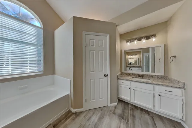 a bathroom with a granite countertop sink a mirror and a bathtub
