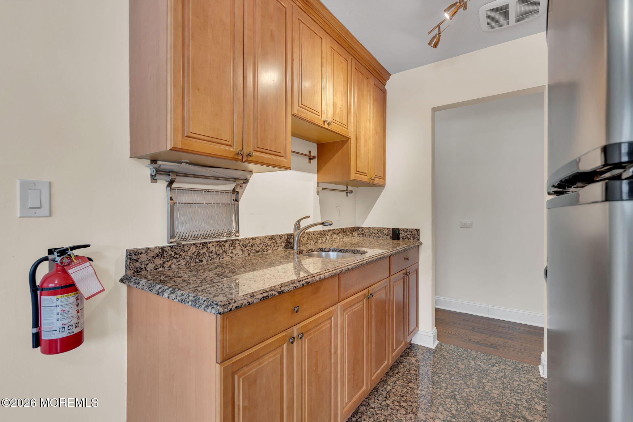 26 Windsor Terrace, Unit E Freehold, NJ 07728 - Photo 20 of 20 a kitchen with stainless steel appliances granite countertop a sink dishwasher and cabinets with wooden floor