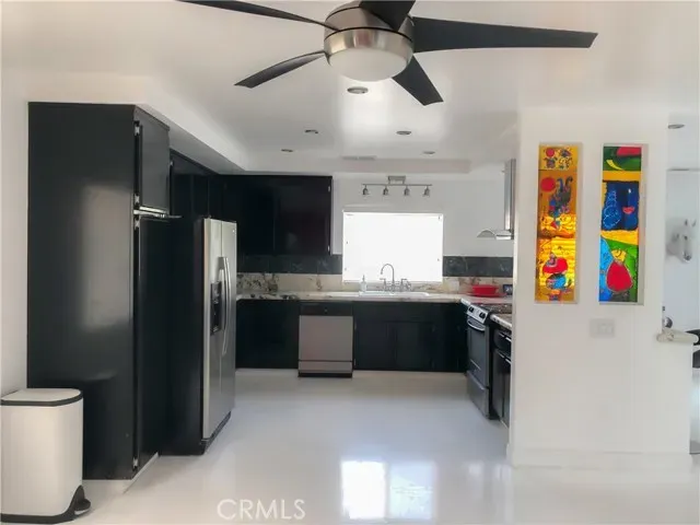 a kitchen with stainless steel appliances kitchen island granite countertop a refrigerator and a sink