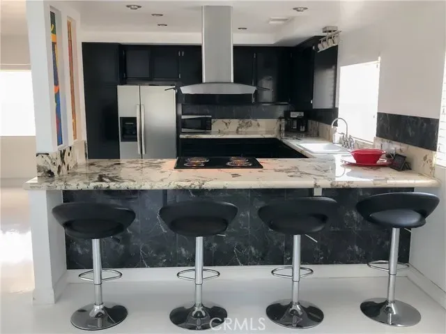 a kitchen with stainless steel appliances kitchen island granite countertop a sink and chairs