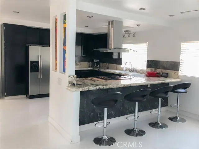 71292 Biskra Road Rancho Mirage, CA 92270 - Photo 9 of 27 a kitchen with stainless steel appliances kitchen island granite countertop a sink refrigerator and cabinets