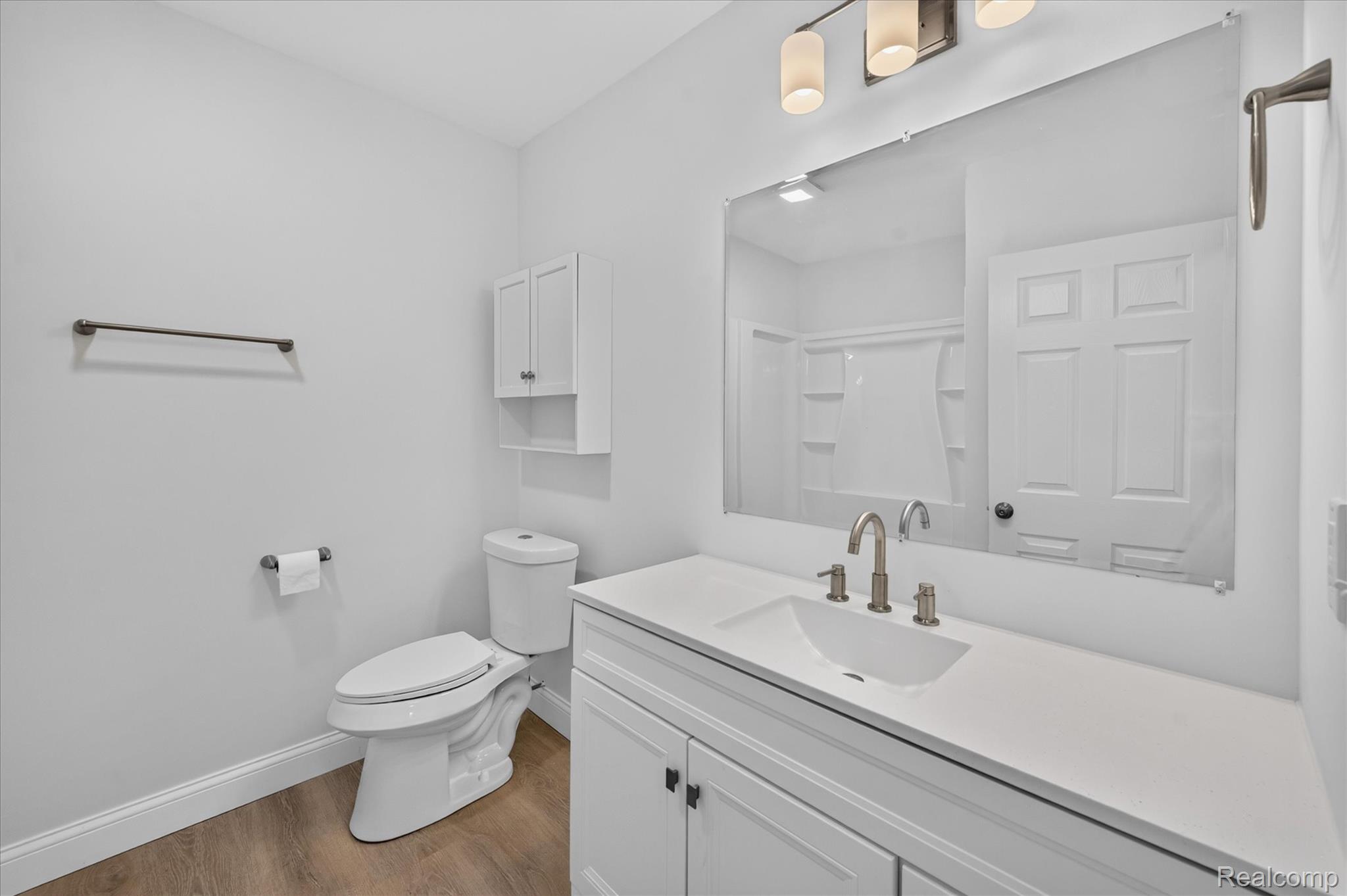 11403 White Lake Road Fenton, MI 48430 - Photo 24 of 36 White vanity with shaker-style cabinetry, an integrated sink, brushed nickel faucet, and a large mirror with overhead lighting