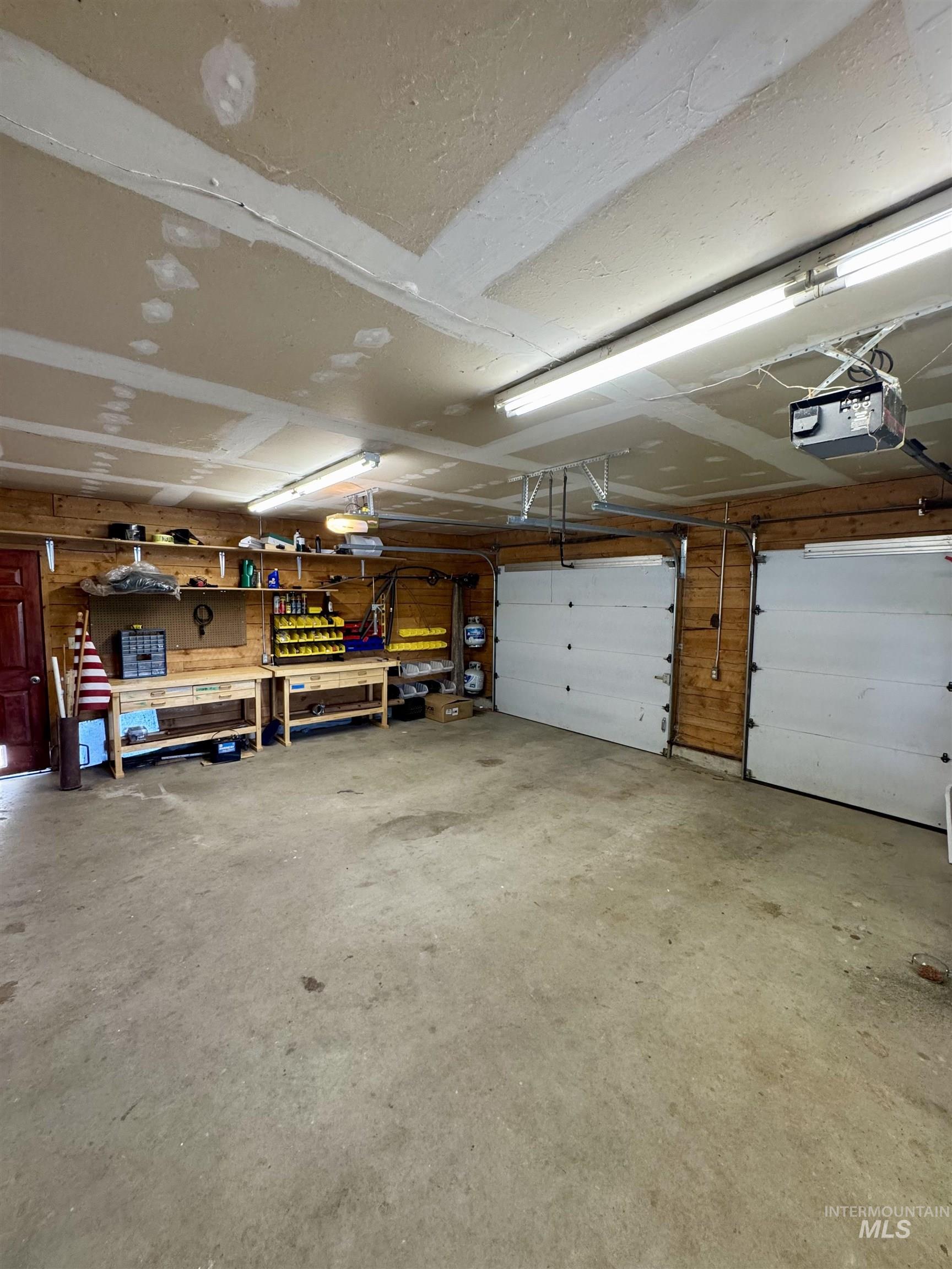 62 Bell Rapids Road Hagerman, ID 83332 - Photo 27 of 34 Spacious garage featuring a concrete floor, horizontal wood paneling, and two overhead doors