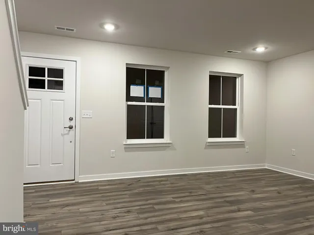 a view of an empty room with wooden floor and windows