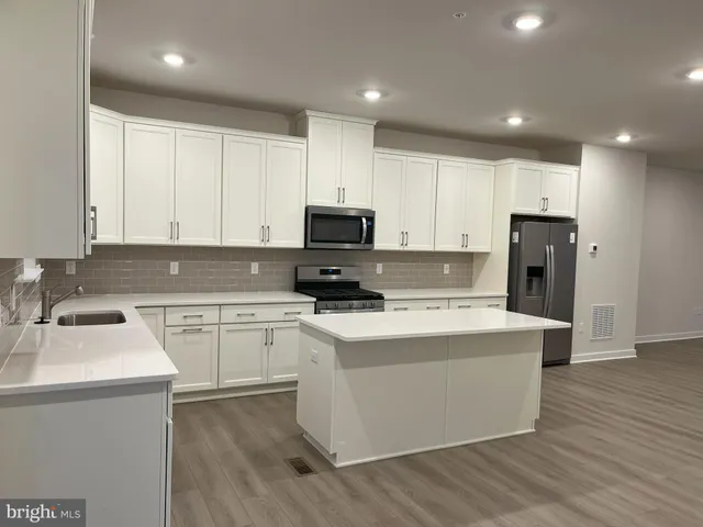 a kitchen with a sink a stove a refrigerator and white cabinets