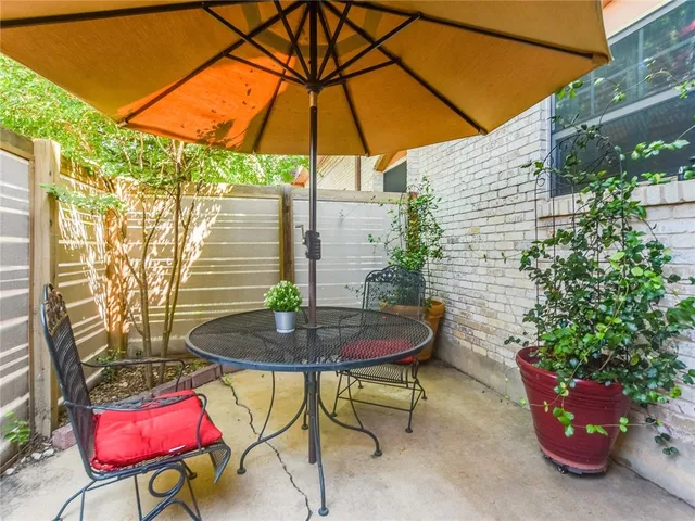 a backyard of a house with table and chairs under an umbrella