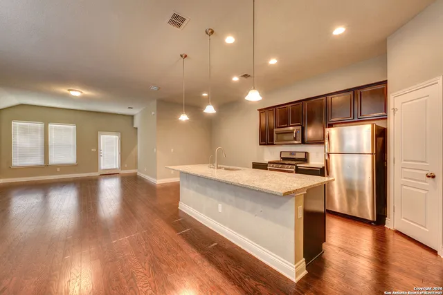 a kitchen with stainless steel appliances granite countertop a refrigerator a sink dishwasher a stove and a refrigerator with wooden floor