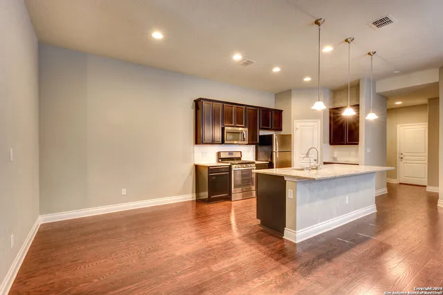 a large kitchen with a large counter top a sink stainless steel appliances and cabinets