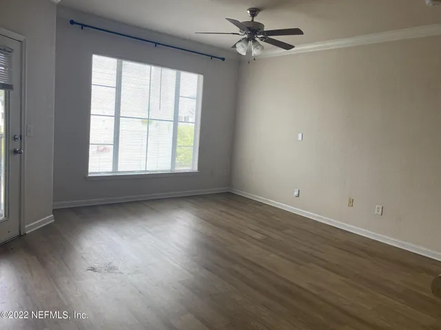 an empty room with wooden floor fan and windows