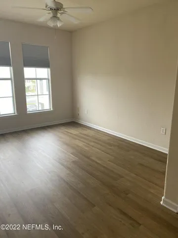 an empty room with wooden floor fan and windows