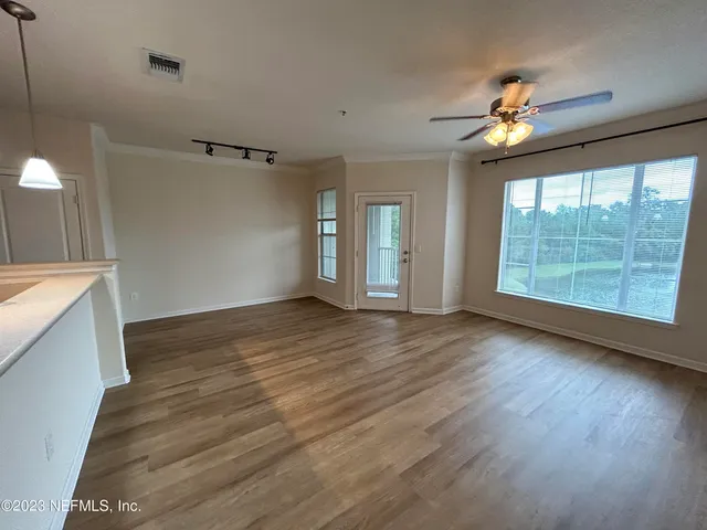 a view of an empty room with wooden floor and a window