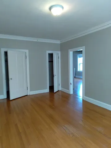 a view of an empty room with wooden floor and closet