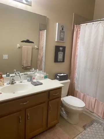 a bathroom with a sink a toilet a mirror and shower curtain